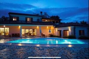 Une maison à deux étages dotée d’une piscine, d’un espace salon extérieur et d  ’une terrasse couverte.