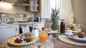 Een ontbijttafel gedekt voor twee personen, met borden vol muffins en bessen, een glas sinaasappelsap en een ananas.