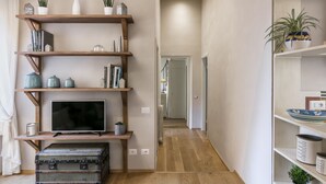 Een gang met houten planken, een televisie en een koffer.