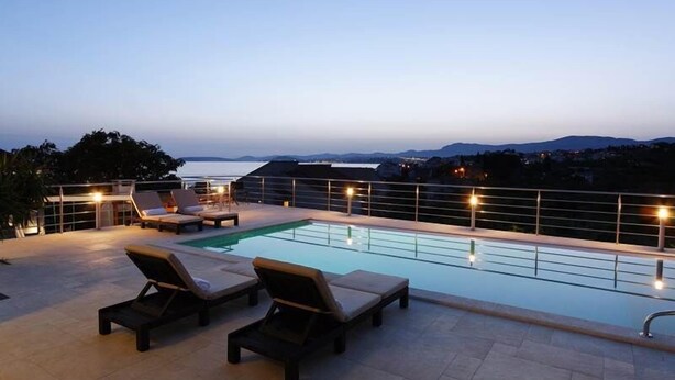A rooftop pool area with lounge chairs and a view of the sea.