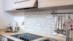 A modern kitchen with a built-in stove, a double sink, and a backsplash of white stone tiles. - Large apartment at Residece Ca of NI - Finalborgo (Finale Ligure)