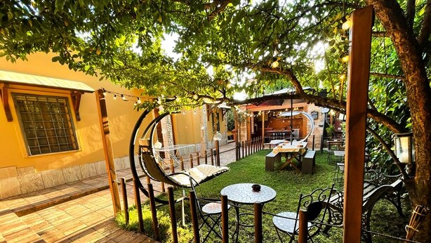 Un patio con piso de madera, una mesa redonda con sillas y césped.