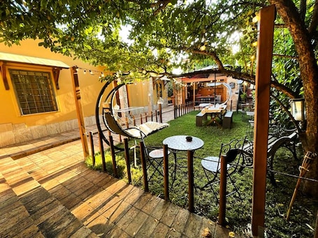 A patio area with a wooden deck, a round table with chairs, and a grassy lawn.