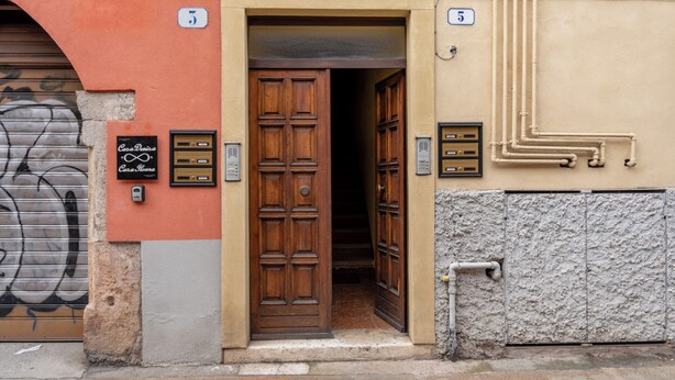 A building entrance with a wooden door, a sign reading "Casa Denisa Casa Denisa," and a number "5" on the wall.