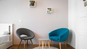 Ein Zimmer mit einem Bett, zwei Stühlen, einem kleinen Tisch und einer weißen Tür.