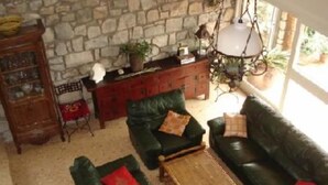 Un salón acogedor con pared de piedra, un mueble de madera y un conjunto de sofá verde.