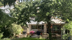 Una casa con fachada de piedra, un porche cubierto y un jardín bien cuidado.