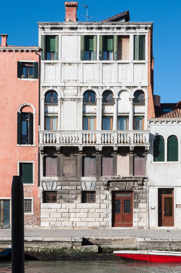 A multi-story building with a balcony, large windows, and a door.