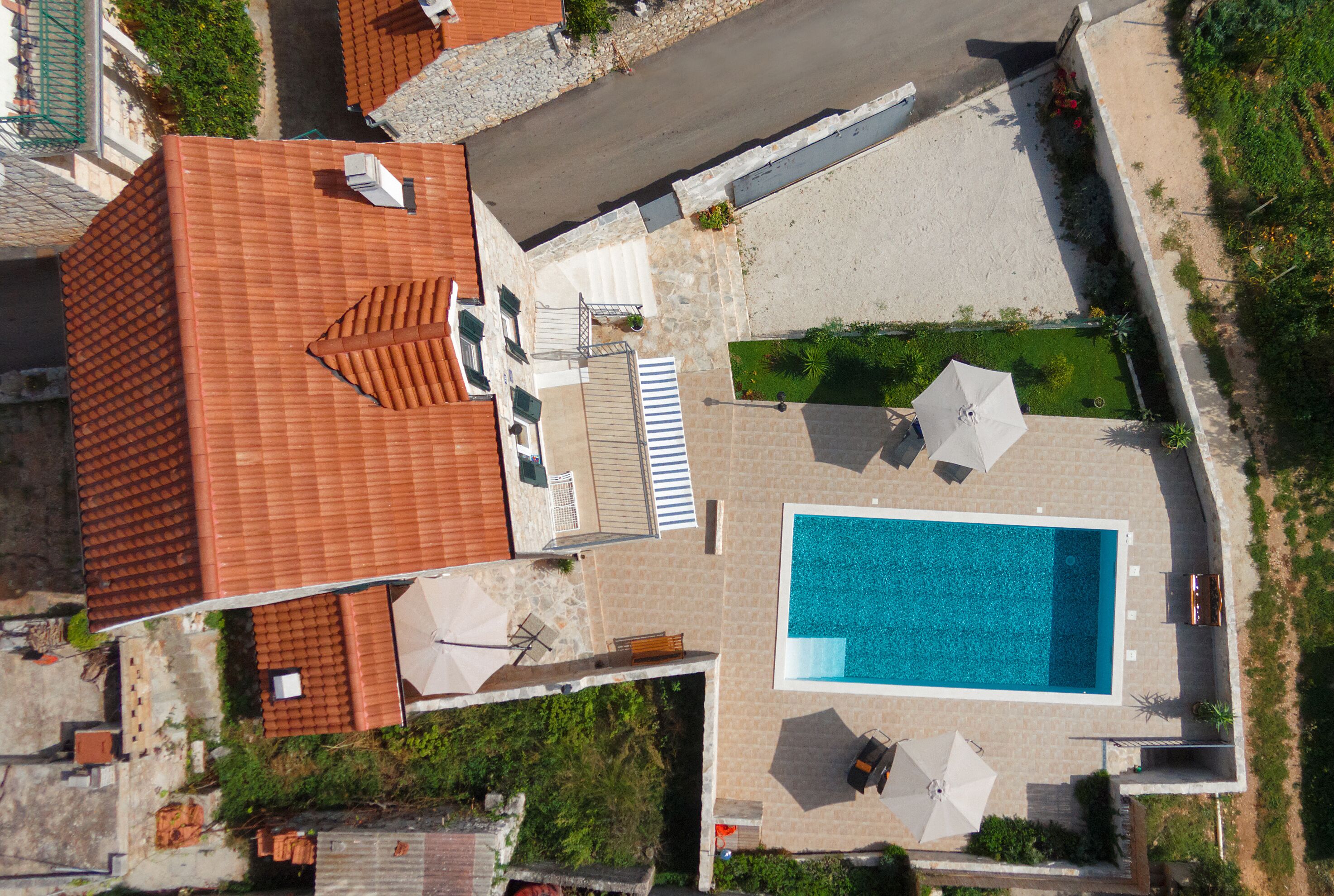 Vista aérea de una propiedad residencial con piscina, mobiliario exterior y tejado de baldosas.