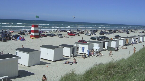 Une plage avec plusieurs caravanes et un phare.