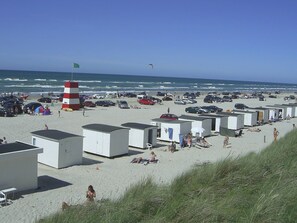 A beach with multiple caravans and a lighthouse.