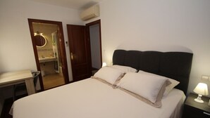 Une chambre d’hôtel avec un lit, un bureau et une salle de bain, visibles à travers une porte ouverte.