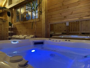 Relax in a cozy cabin-style room with a central hot tub and natural touches.
