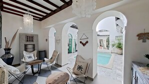 A spacious indoor area with a pool, featuring a modern design with white walls, wooden beams, and a mix of seating arrangements including chairs and a table. - RIAD 16 PEOPLE - HEART OF MEDINA, HOTEL SERVICE, HEATED POOL, JACUZZI SPA (Marrakesh)
