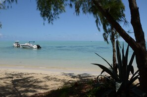 A beach with a boat on the shore and a clear view of the ocean.