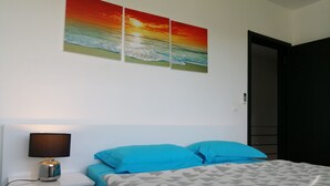 A bedroom with a bed, a nightstand, a lamp, and three wall-mounted paintings of a sunset over the ocean. - CHARMING VILLA WITH SWIMMING POOL NEAR THE BEACH (Albion)