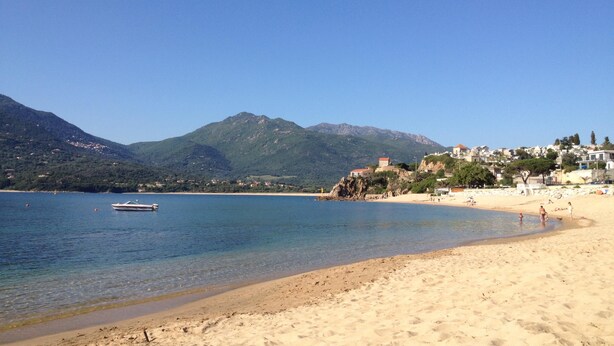 A beach with clear water, a boat, and mountains in the background. - SUPERB AIR-CONDITIONED APARTMENT ON THE BEACH WITH PARADISIAC WATERFRONT VIEW (Propriano)