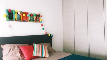 Relax in this inviting bedroom with a comfortable bed, colorful wall hanging, and stylish wardrobe.