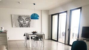 A modern living room with a sofa, a dining area, and a television. - SUPERB AIR-CONDITIONED APARTMENT ON THE BEACH WITH PARADISIAC WATERFRONT VIEW (Propriano)