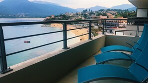 A balcony with blue chairs overlooking a beach and mountains. - SUPERB AIR-CONDITIONED APARTMENT ON THE BEACH WITH PARADISIAC WATERFRONT VIEW (Propriano)