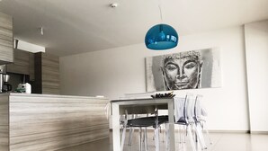 A modern kitchen with a wooden countertop, a dining area with a glass table and chairs, and a blue pendant light. - SUPERB AIR-CONDITIONED APARTMENT ON THE BEACH WITH PARADISIAC WATERFRONT VIEW (Propriano)