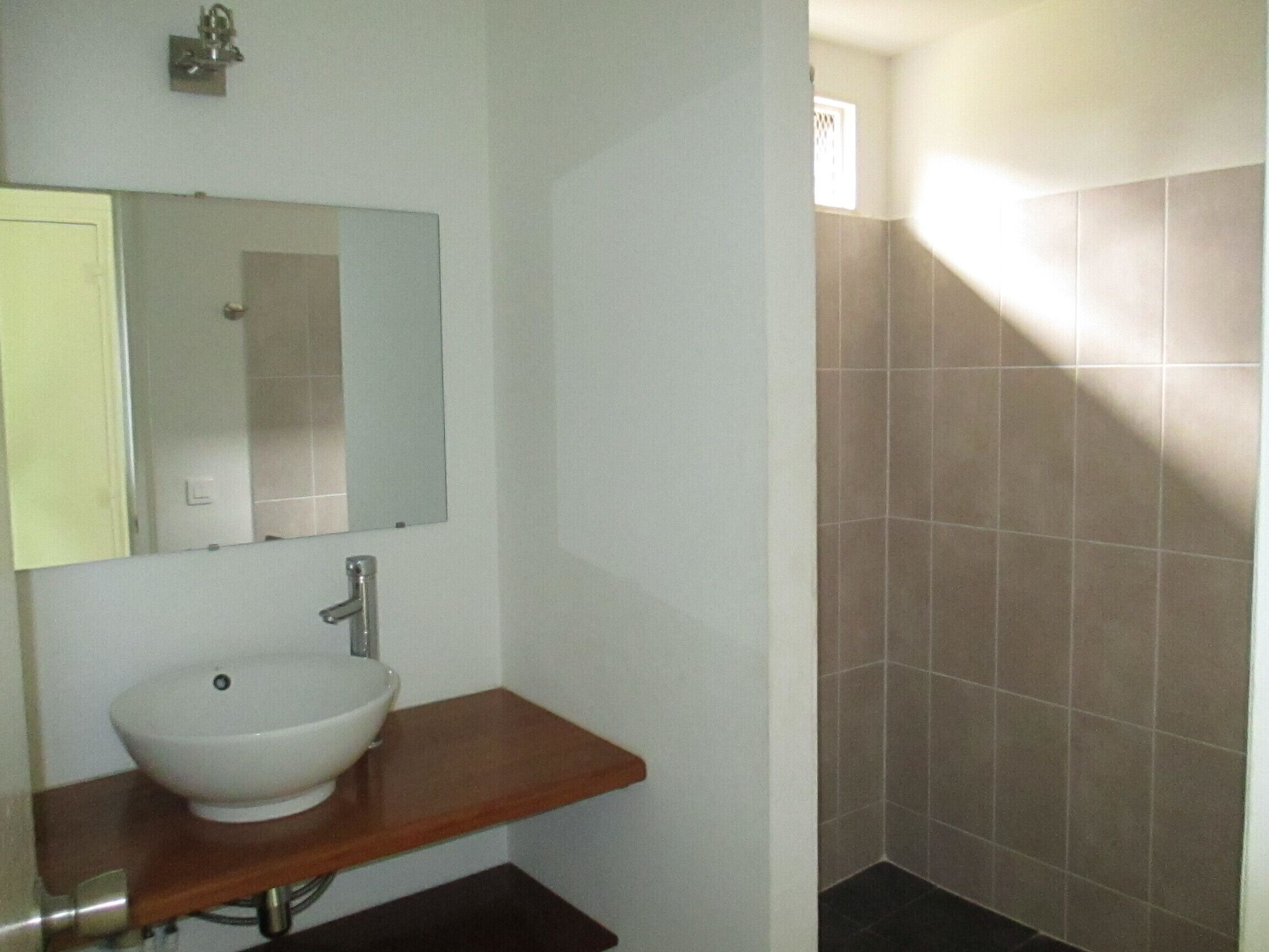Un baño con un lavamanos blanco, un espejo y una encimera de madera.