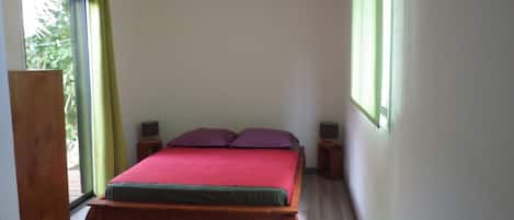 Une chambre à coucher avec un lit en bois, deux tables de chevet et une fenêtre avec des rideaux.