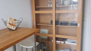 A kitchenette with a wooden cabinet, a white table, and stools. - Furnished apartment.  Close to the beach and shops.  (Berck)