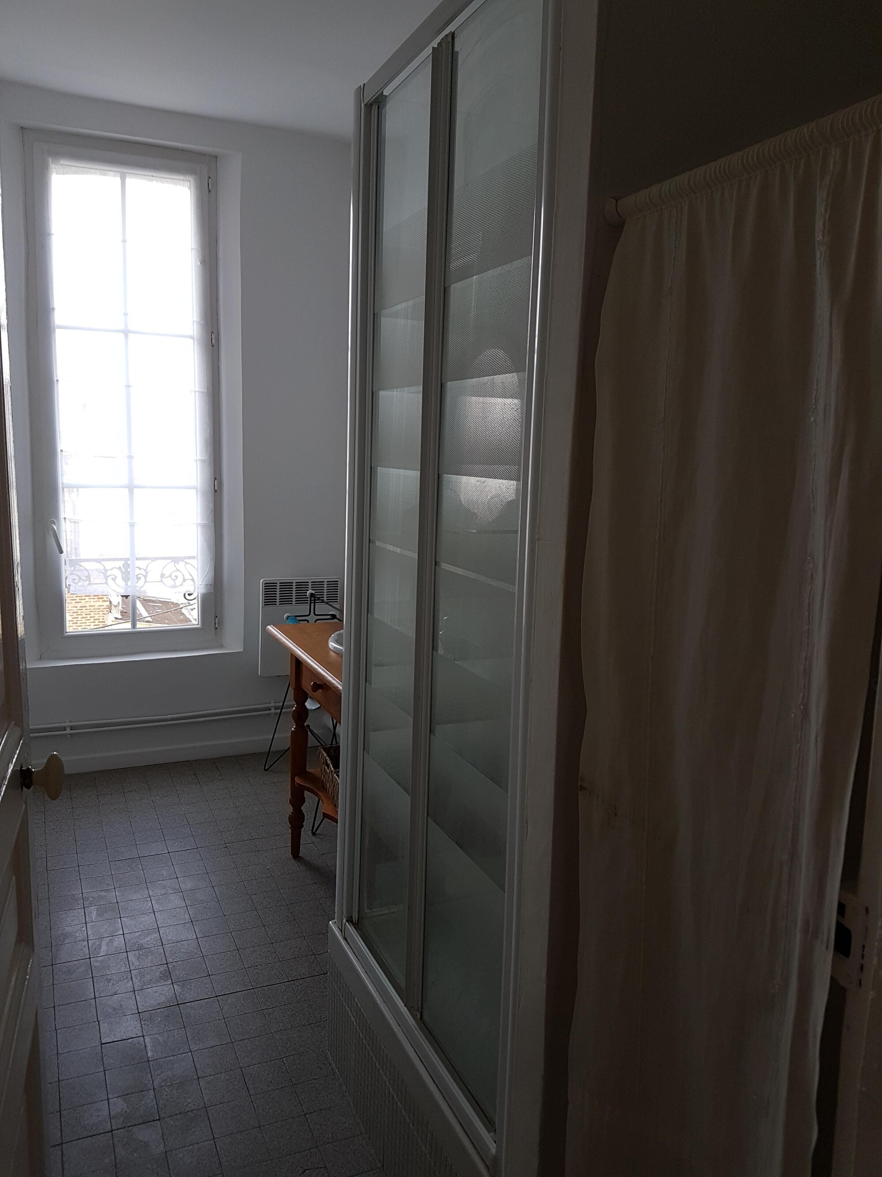 A room with a large window, a sliding glass door, and a wooden desk.