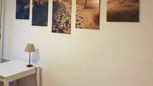 A room with a white desk, a lamp, and four beach-themed paintings on the wall. - Furnished apartment.  Close to the beach and shops.  (Berck)