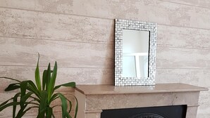 A room with a fireplace, a potted plant, and a mirror on the wall. - Furnished apartment.  Close to the beach and shops.  (Berck)