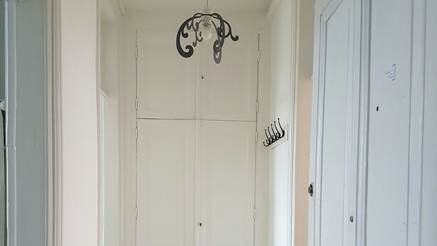 A hallway with wooden flooring, white doors, and a decorative ceiling light fixture. - Furnished apartment.  Close to the beach and shops.  (Berck)
