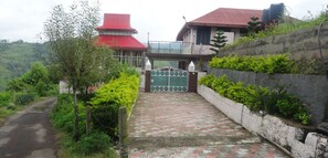 A gated entrance with a paved pathway leading to a building with a red roof.