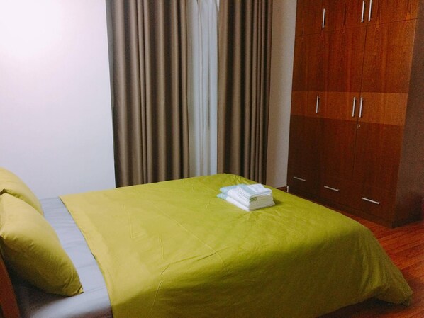 Una habitación de hotel con cama, un armario de madera y cortinas.