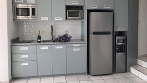 Una cocina moderna con armarios grises, un refrigerador de acero inoxidable, un microondas y un horno empotrado.