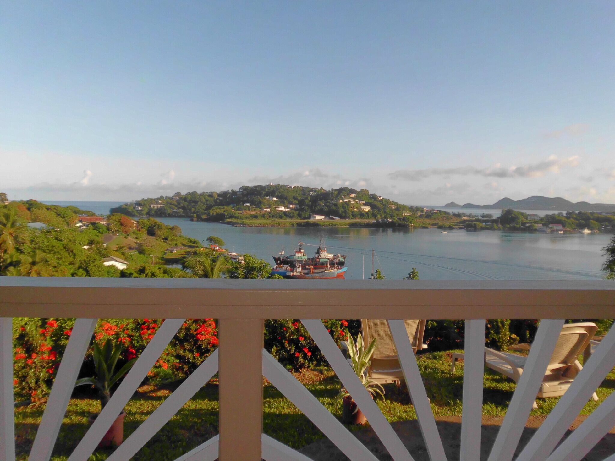 Vista de um lago com um barco, rodeado por vegetação e casas.