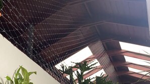 Een hoge plafond met een metalen gaas en uitzicht op de lucht via dakramen.