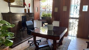 Een eetgedeelte met een houten tafel, stoelen, een plant in pot en een kast.