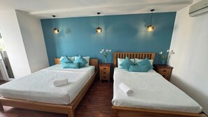 A hotel room with two wooden beds, teal walls, and pendant lights. - FAMILY APARTMENT IN HO CHI MINH CITY (Hồ Chí Minh)