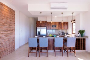 A modern kitchen with a central island, wooden cabinets, and pendant lighting.