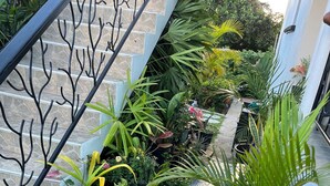 A staircase with a metal railing, surrounded by potted plants and greenery. - The Palms Areca-Attractive, Alluring and Aesthetically artistic (Bridgetown)