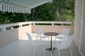 Relax in a serene outdoor space with a table and chairs, surrounded by lush greenery and a shaded area.