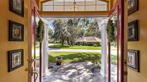 A covered entrance with a view of a well-maintained lawn and a house in the background. - Luxurious Home w/ Spectacular Glass Room & Patios (Orange Park)