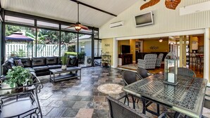 A spacious patio with a black leather sofa, a dining table with metal chairs, and a decorative lantern. - Luxurious Home w/ Spectacular Glass Room & Patios (Orange Park)