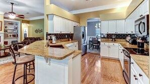 A spacious kitchen with white cabinets, granite countertops, and stainless steel appliances. - Luxurious Home w/ Spectacular Glass Room & Patios (Orange Park)