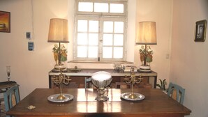 A dining table with two lamps, a window, and a decorative statue.