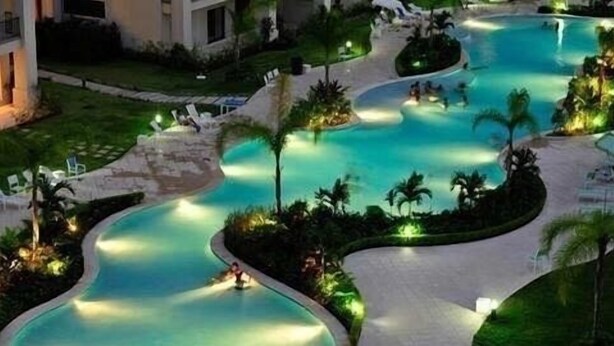 Et resort med flere swimmingpools, palmer og liguestole.