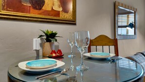 Un tavolo da pranzo con piatti, posate e bicchieri, una pianta in vaso e un quadro appeso al muro.