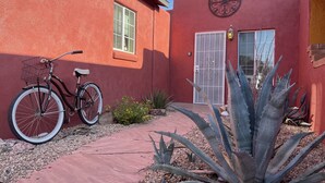 Un edificio rosso con una bicicletta parcheggiata fuori, una porta e una finestra.