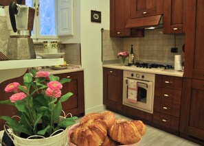 A kitchen with wooden cabinets, a stove, and a sink. There are flowers and pastries on the counter. - *Fantastic** 2 Bedroom Apartment In Center Of Rome. Beautifully Remodeled! (Rome)